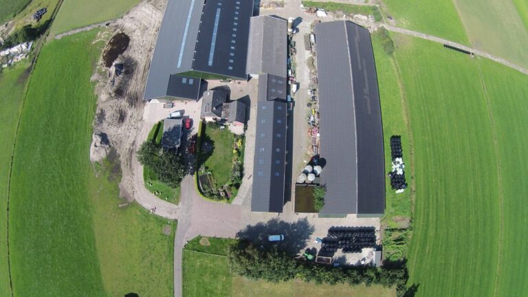 Luchtfoto van stallen met Landini golfplaten in Nunspeet